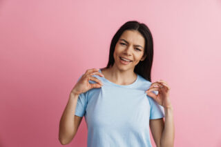 Young hispanic woman smiling and holding her t-shirt